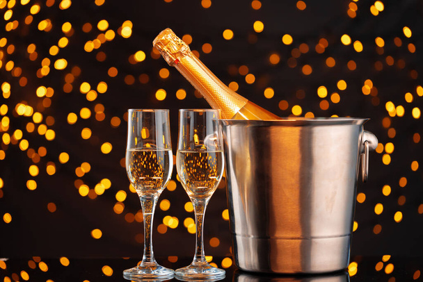 Champagne bottle and glasses on blurred lights background - Foto, imagen
