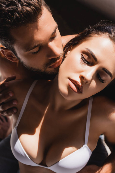 hoge hoek uitzicht van shirtless man aanraken jonge sexy vrouw met gesloten ogen - Foto, afbeelding