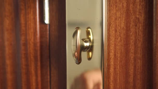 Hombre cerrando una cerradura de puerta de bronce de cerca en una puerta de madera oscura. Concepto de seguridad doméstica y robo - Metraje, vídeo