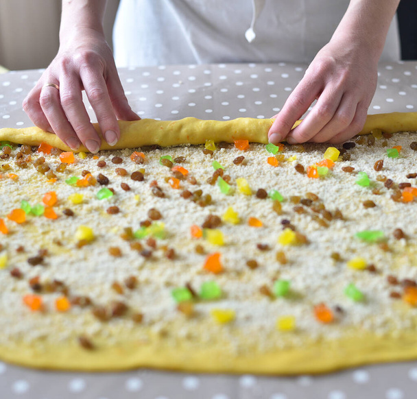 female hands twist the dough with raisins and candied fruits. raw cake dough - Photo, Image