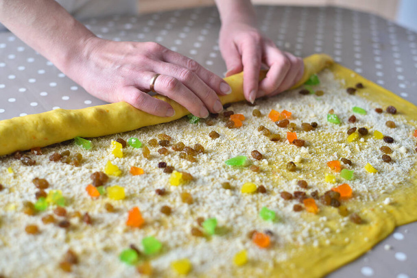 Kadın eli hamuru kuru üzüm ve şekerli meyvelerle çevirir. çiğ kek hamuru - Fotoğraf, Görsel