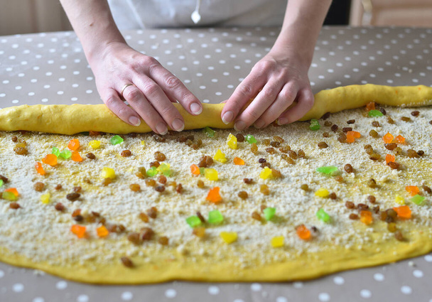female hands twist the dough with raisins and candied fruits. raw cake dough - Photo, Image