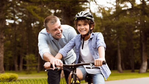 Chłopiec uczy się jeździć na rowerze ze ze swoim szczęśliwym ojcem - Zdjęcie, obraz