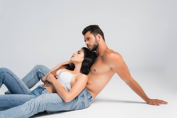 shirtless man and woman in bra lying on grey - Фото, зображення