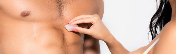 panoramic crop of woman holding ice cube near torso of shirtless man isolated on white - Foto, Imagem