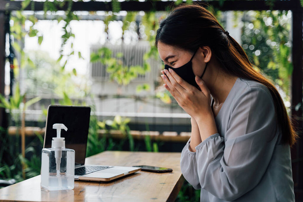 One 20s young adult business woman sneezing with tissue handkerchief. Casual female freelancer working with laptop outdoors with alcohol gel on desk. With copy space - Fotografie, Obrázek