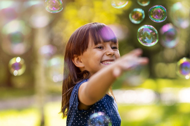 Дівчина грає з мильними бульбашками на відкритому повітрі
 - Фото, зображення