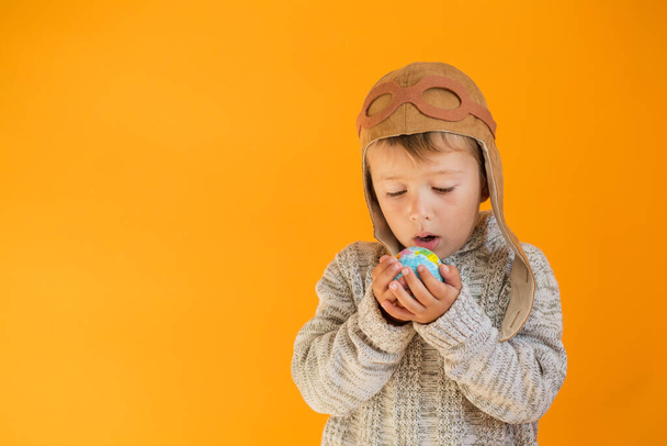 Літлє хлопчик в шоломі з землею в руках на помаранчевому фоні
 - Фото, зображення