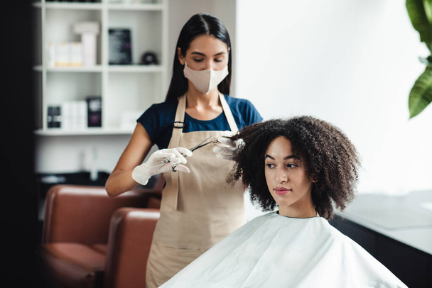 African american woman getting haircut from master in protective mask, free space - Photo, Image