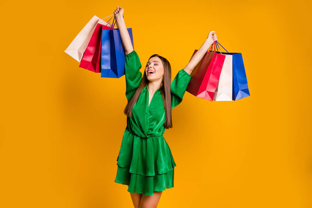 Portrait of her she nice attractive lovely cheerful glad straight-haired girl carrying new things clothes having fun rising hands up isolated over bright vivid shine vibrant yellow color background - Photo, Image