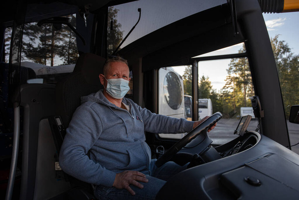 Busfahrer mit medizinischer Maske, Blick aus dem Busfenster Sicheres Autofahren während einer Pandemie, Schutz vor Coronavirus - Foto, Bild