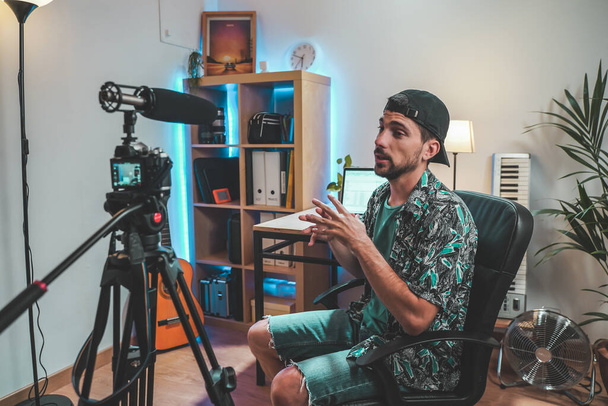 Behind the scene shot of a young man influencer making a video. Very handsome man with beard shooting a video for social media talking directly to the camera. Influencer's amazing work space. - Foto, immagini