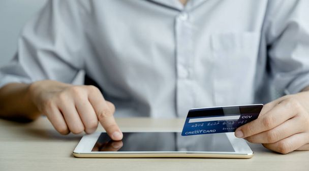 Kreditkarte in der Hand der Geschäftsfrau für Online-Shopping auf dem Tablet von zu Hause aus, E-Commerce-Bezahlung, Internet-Banking, Geld für den nächsten Urlaub ausgeben. - Foto, Bild