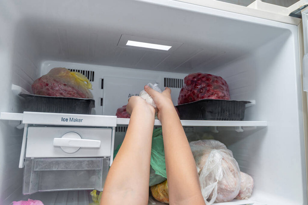 La mujer saca comida congelada del congelador.. - Foto, imagen