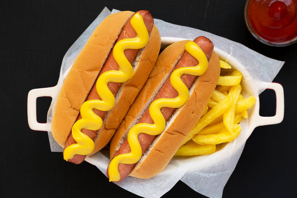 Domácí hořčice Hot Dog a hranolky na černém pozadí, pohled shora. Plocha ležela shora, shora. - Fotografie, Obrázek