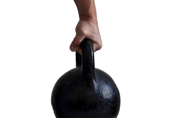 La mano de un hombre sosteniendo firmemente un peso de hierro fundido por el mango aislado. - Foto, imagen