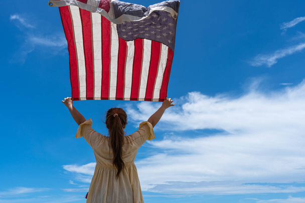 femme debout et tenant drapeau des États-Unis sous le ciel bleu. - Photo, image