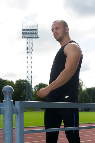 Image of muscle man stretching on stadium - Foto, afbeelding