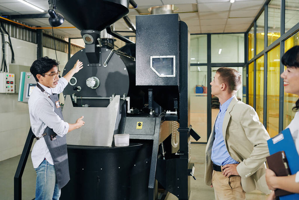 Káva pražírna pracovník ukazuje nový stroj pro investora a mluvit o jeho výhodách - Fotografie, Obrázek