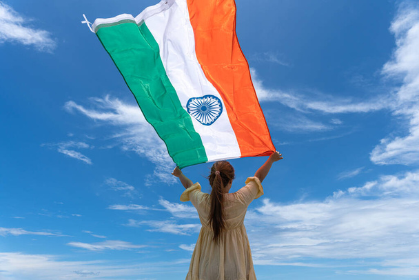 femme debout et tenant drapeau de l'Inde sous le ciel bleu. - Photo, image