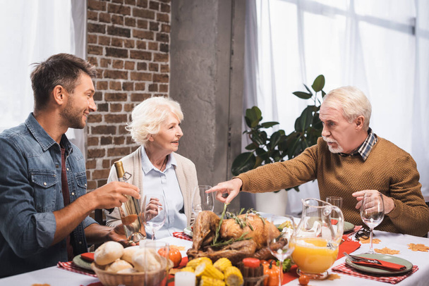 senior man pointing with finger while celebrating thanksgiving with family at served table - Foto, afbeelding