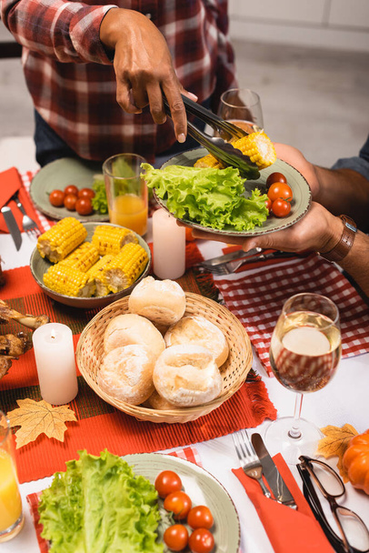 обрезанный вид африканской американки положить овощи на тарелку во время празднования Дня благодарения - Фото, изображение