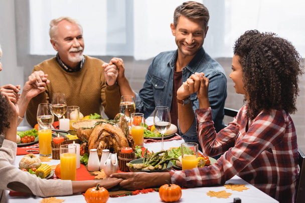 men looking at african american woman while holding hands on thanksgiving - Photo, Image