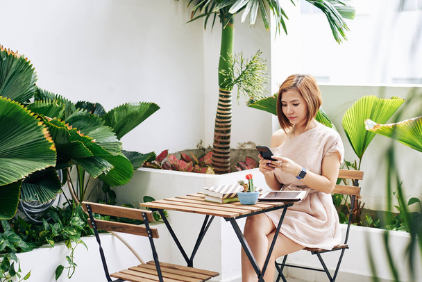 Bella giovane donna vietnamita scattare foto di cactus e libri sul tavolo del caffè per i suoi social media - Foto, immagini