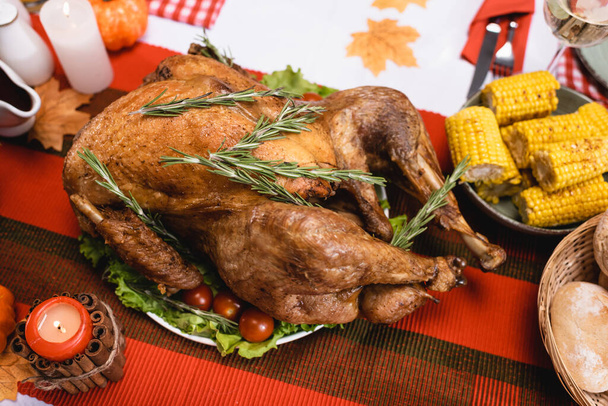 Selective focus of tasty turkey on table near candles and corn  - Foto, Bild