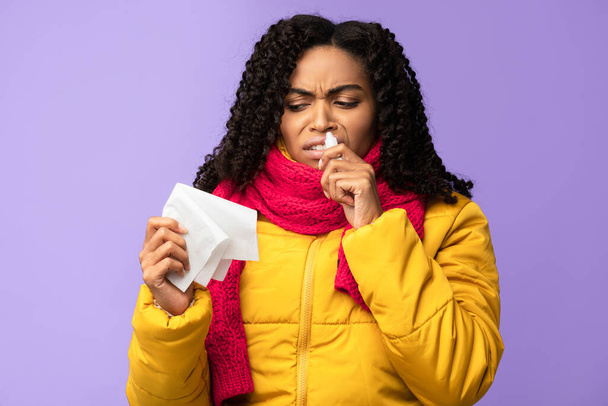 Kranke schwarze Frau macht Nasenstilisation vor lila Hintergrund - Foto, Bild