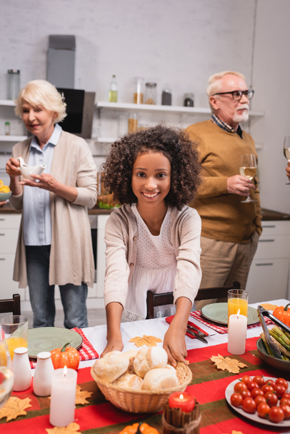 Selective focus of african american girl holding buns near grandparents during thanksgiving  - Φωτογραφία, εικόνα