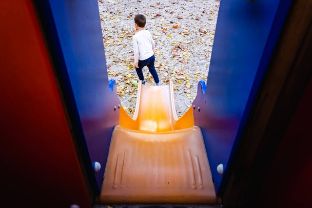Child sliding down a slide, seen from the back from above. - Photo, Image