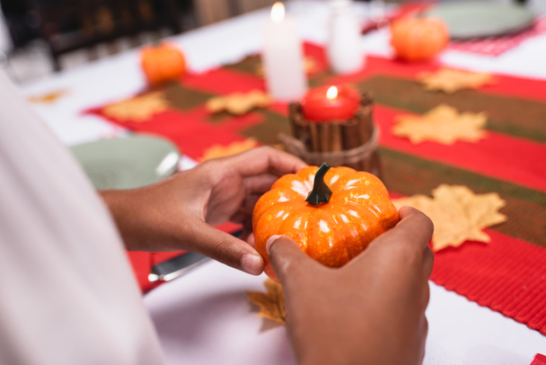 Cropped view of african american child holding decorative pumpkin during thanksgiving celebration  - Photo, image