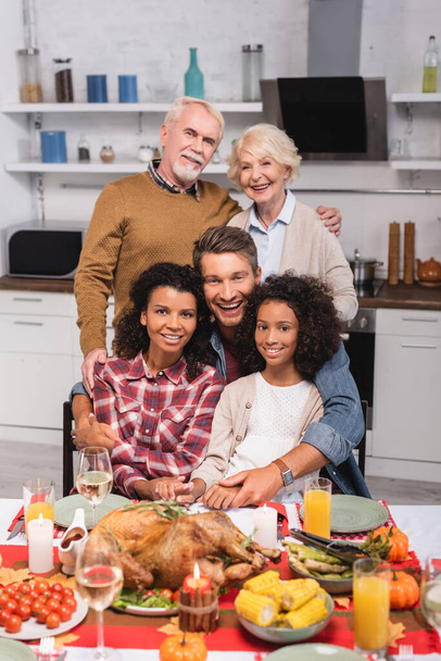 Selective focus of multicultural family embracing during thanksgiving celebration  - Foto, Imagem