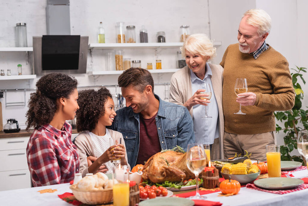 Selective focus of multicultural family celebrating thanksgiving near food on table  - Photo, Image