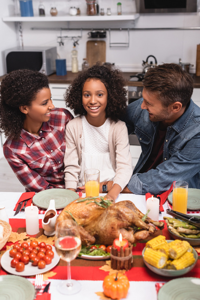 Selectieve focus van multi-etnische ouders op zoek naar Afrikaanse Amerikaanse dochter tijdens thanksgiving thuis  - Foto, afbeelding