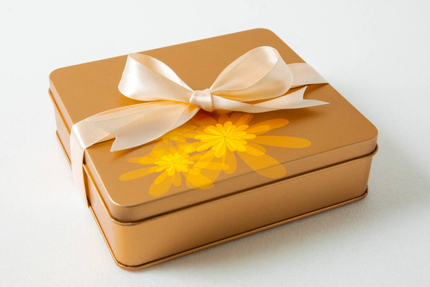 Μεσοφθινοπωρινό φεστιβάλ χρυσό κουτί δώρου δεμένο με σατέν κορδέλα σε λευκό φόντο - Φωτογραφία, εικόνα