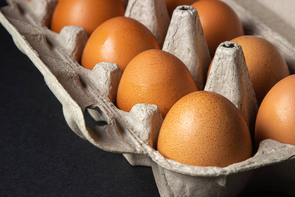 Huevos sobre fondo negro. Huevos de pollo en una caja de papel - Foto, Imagen