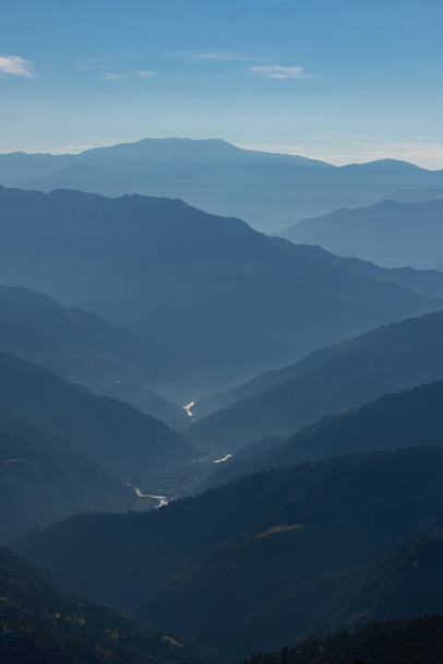 Silhouette of mountain ranges with a river flowing through them during an early morning at Sikkim India - Foto, imagen
