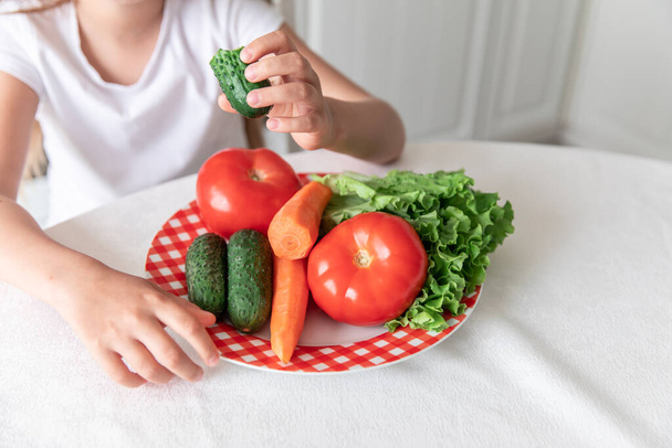 A menina come vegetais na cozinha. saudável. vegetarianismo. criança come alimentos vegetais - Foto, Imagem