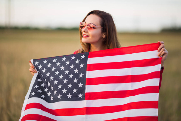 beautiful young woman in pink sunglasses with american flag - Foto, Bild