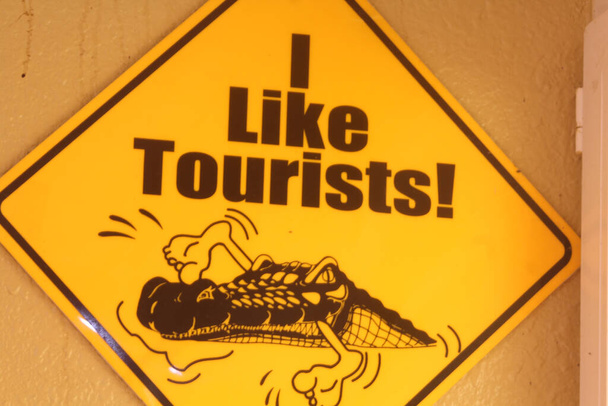 un segno umoristico che mostra un coccodrillo che dice: Mi piacciono i turisti! - Foto, immagini