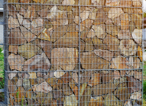 Gabionenzaun mit Natursteinen im Inneren. - Foto, Bild