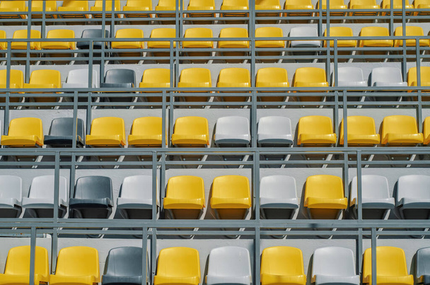Sillas amarillas y grises en el podio deportivo para espectadores. - Foto, Imagen