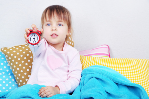 Little girl sitting on pillows on wall background - Foto, Imagem
