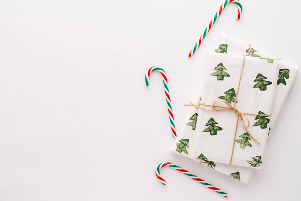 Рождественская композиция Подарки, красные и зеленые рождественские конфеты, украшения на белом фоне. Концепция Рождества, зимы, Нового года. Плоский стеллаж, вид сверху, пространство для копирования - Фото, изображение