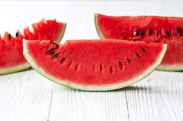 Fresh sliced watermelon and watermelon pieces on a wooden background. - Photo, Image