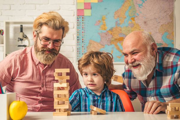 Male generations friendship. Laughing grandparent with son and grandchild relaxing spending weekend at home. Playing Jenga. - Φωτογραφία, εικόνα