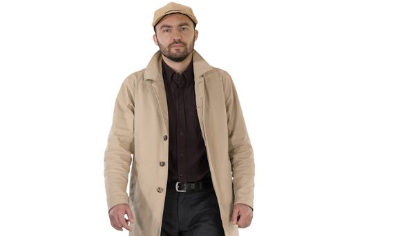 Fashionable man with dark beard in trench coat walking on white background. - Foto, Imagen