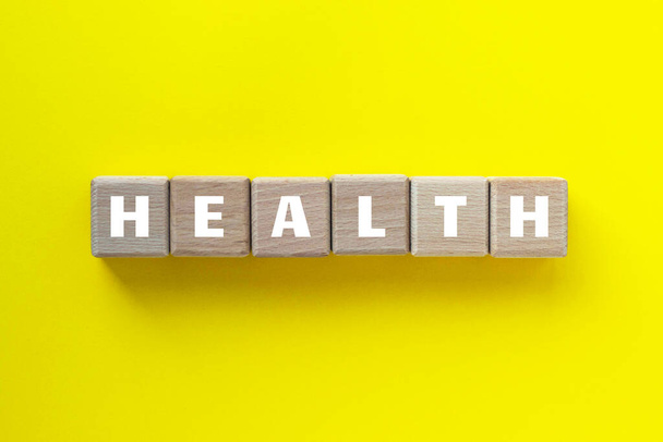 木の立方体に書かれた健康的な言葉。黄色の背景に木製のブロック。医療・健康の概念. - 写真・画像